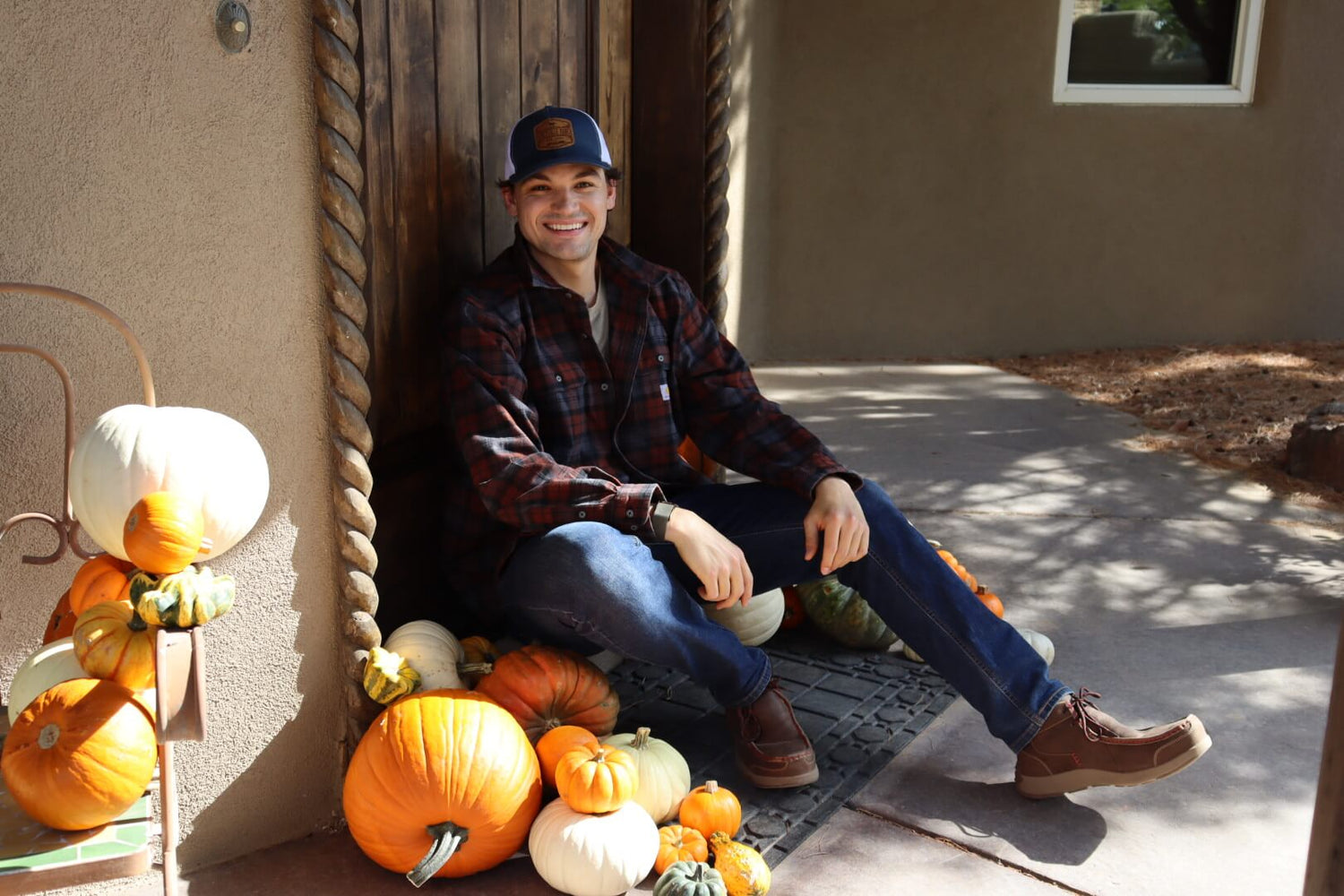 picture of man sitting on a porch decorated with pumkpins for fall